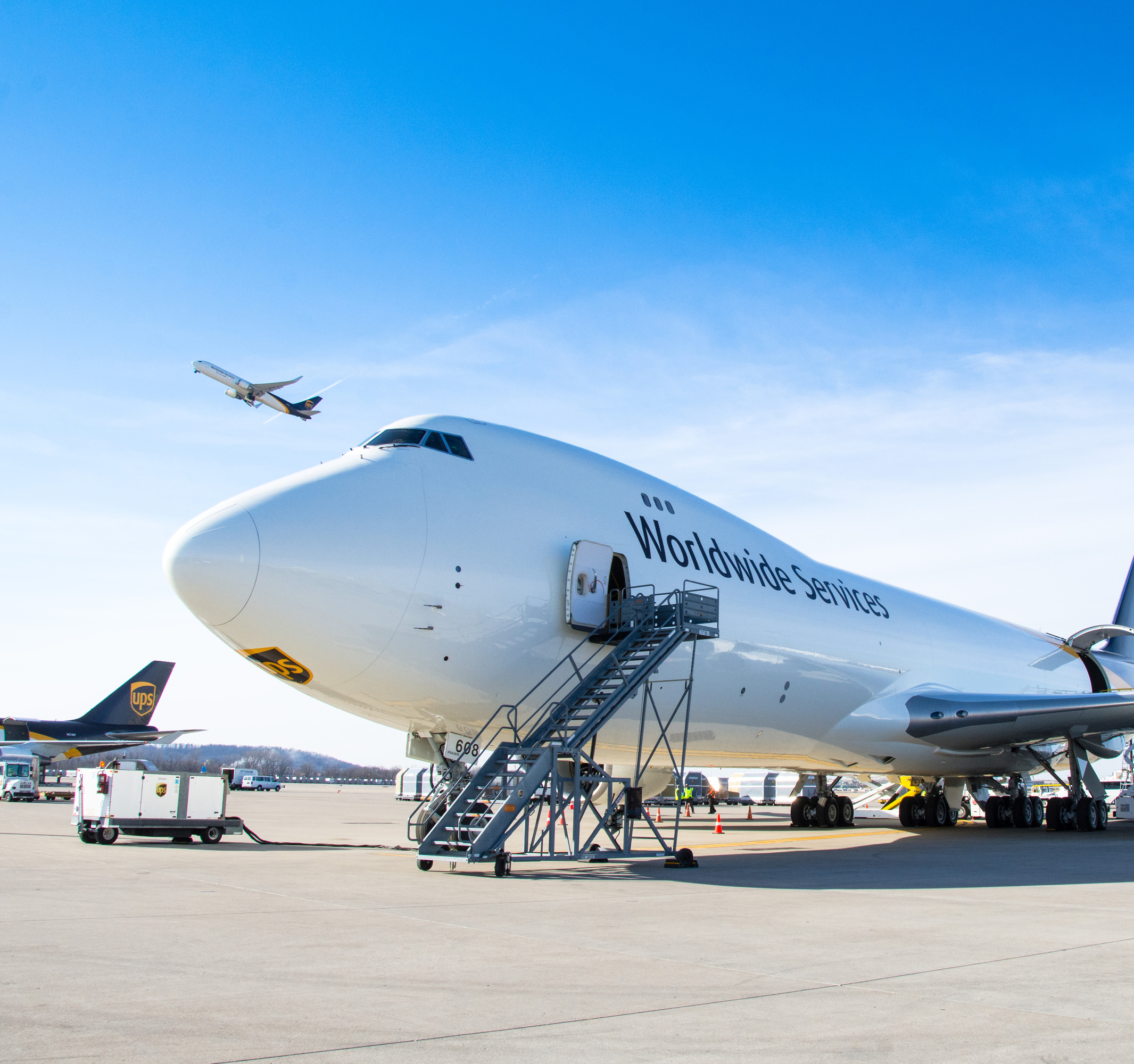 A large cargo airplane is parked on an airport tarmac under a clear blue sky.