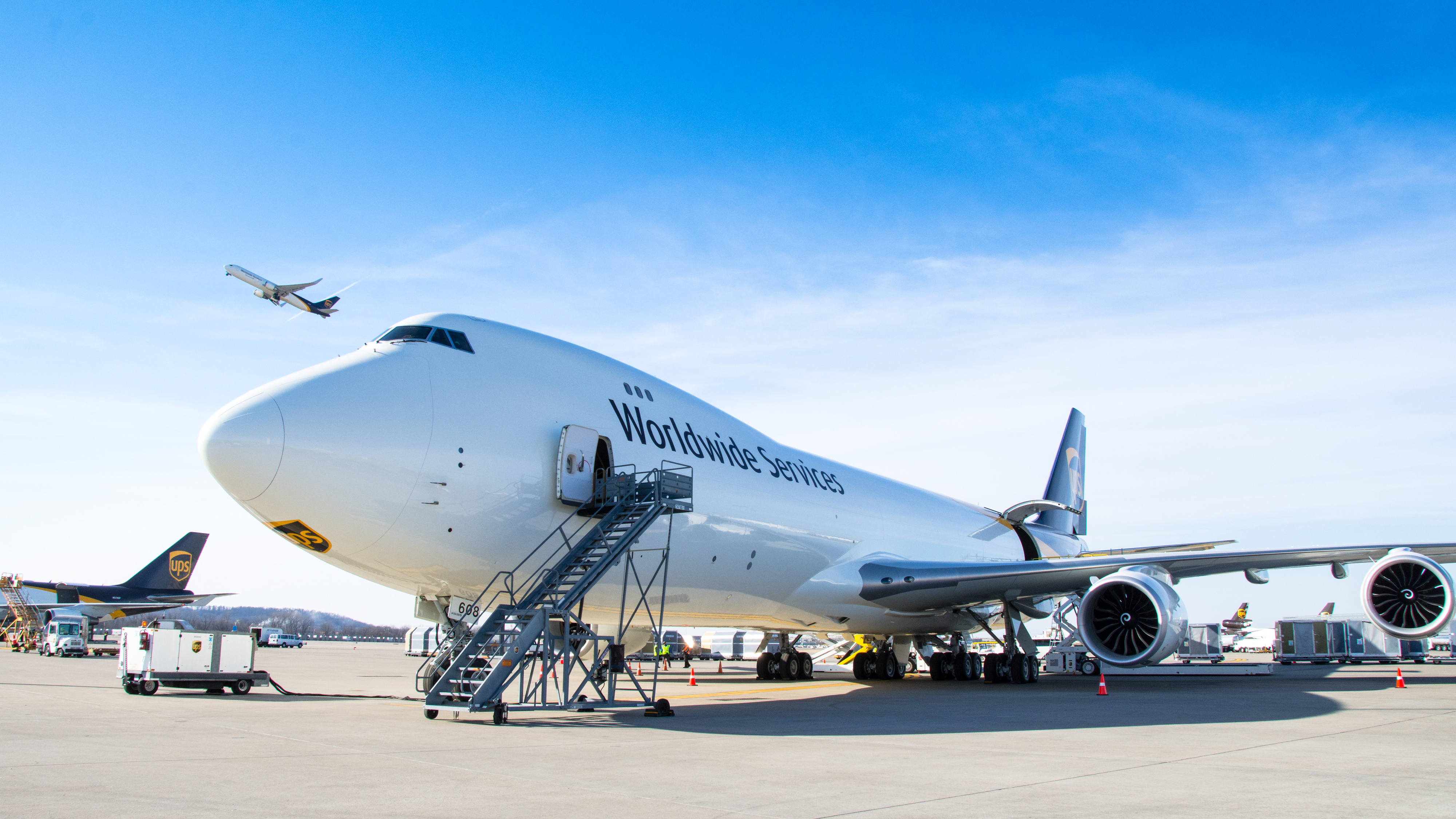 A large cargo airplane is parked on an airport tarmac under a clear blue sky.