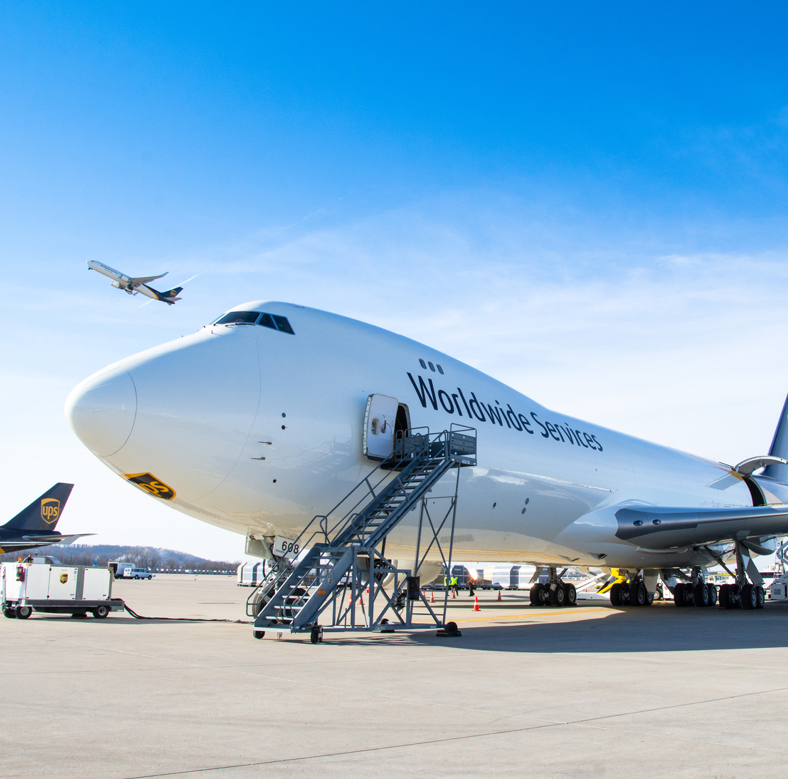 A large cargo airplane is parked on an airport tarmac under a clear blue sky.