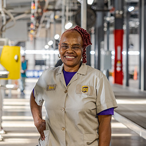Nhân viên toàn thời gian của UPS mỉm cười đứng trong một cơ sở xe tải