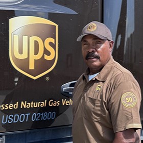 Smiling UPS Circle of Honor member posing with a white shipping box