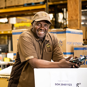 Miembro del Círculo de Honor de UPS sonriente posando con una caja de envío blanca