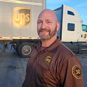 微笑的 UPS 榮譽圈運務員，站在大型聯結車前