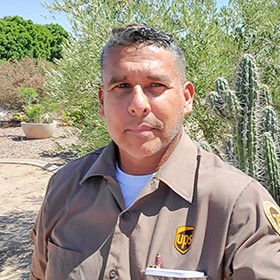 Smiling UPS Circle of Honor driver standing in front of his big rig