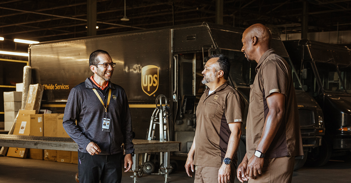 A group of UPS employees talking together in a facility.