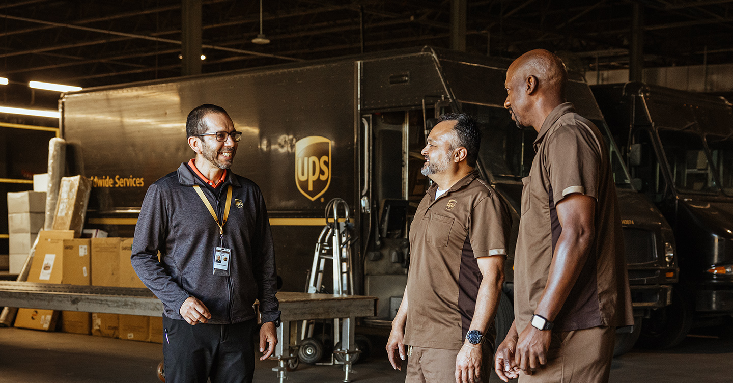 Een groep UPS-werknemers die met elkaar praten in een faciliteit.