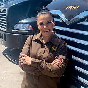 Smiling woman with crossed arms in front of her UPS big rig.