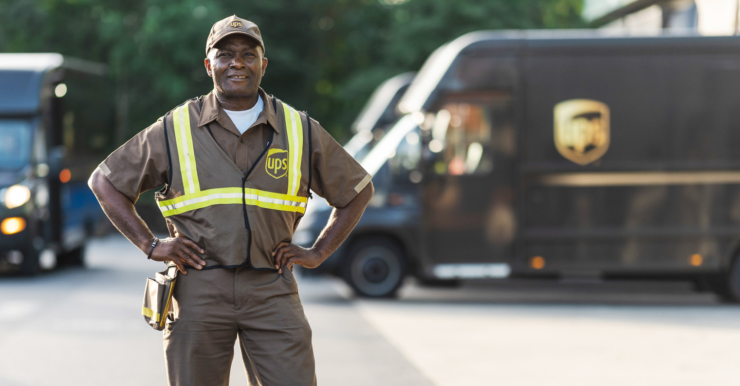 UPS delivery driver Charles Ohagwu in uniform with lorries in the background.