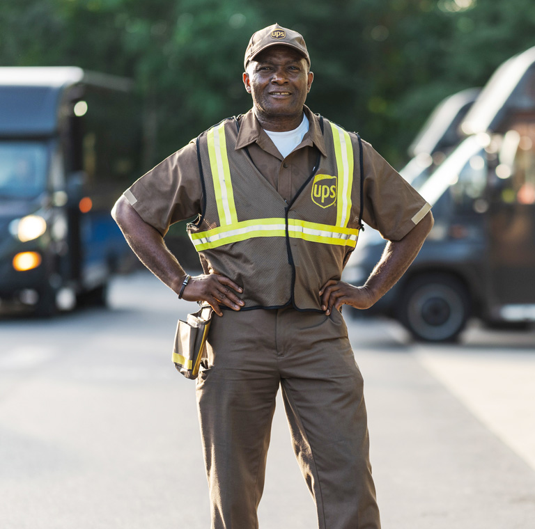 UPS delivery driver Charles Ohagwu in uniform with lorries in the background.