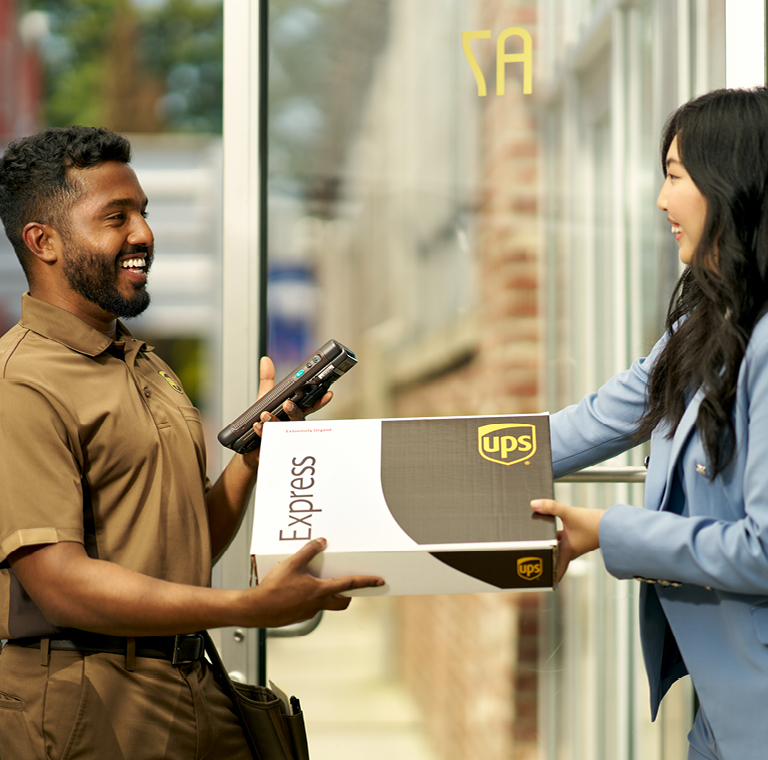 UPS delivery person hands a package to a woman in a blue blazer