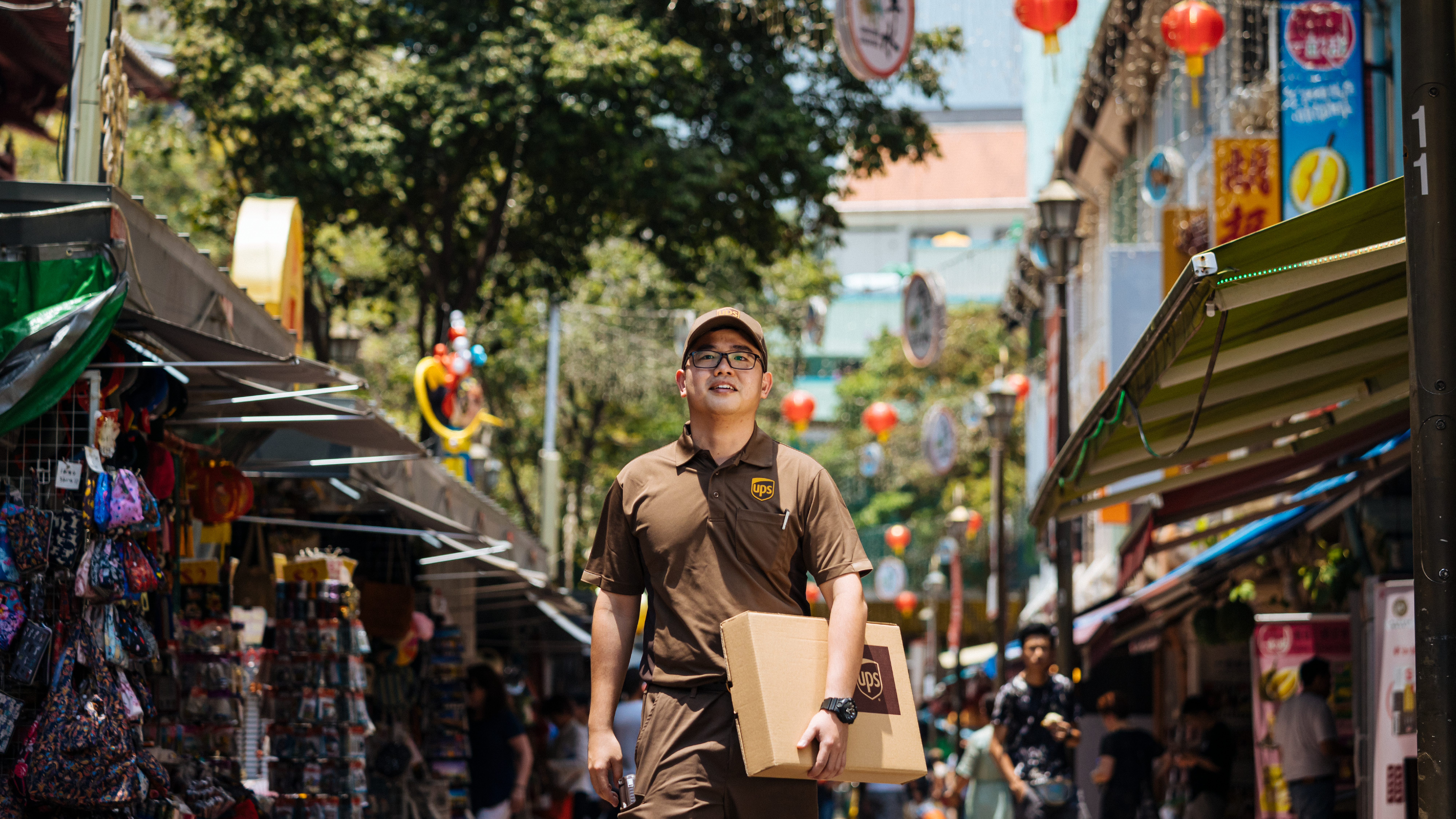 Un livreur UPS transportant un colis dans un marché urbain très fréquenté