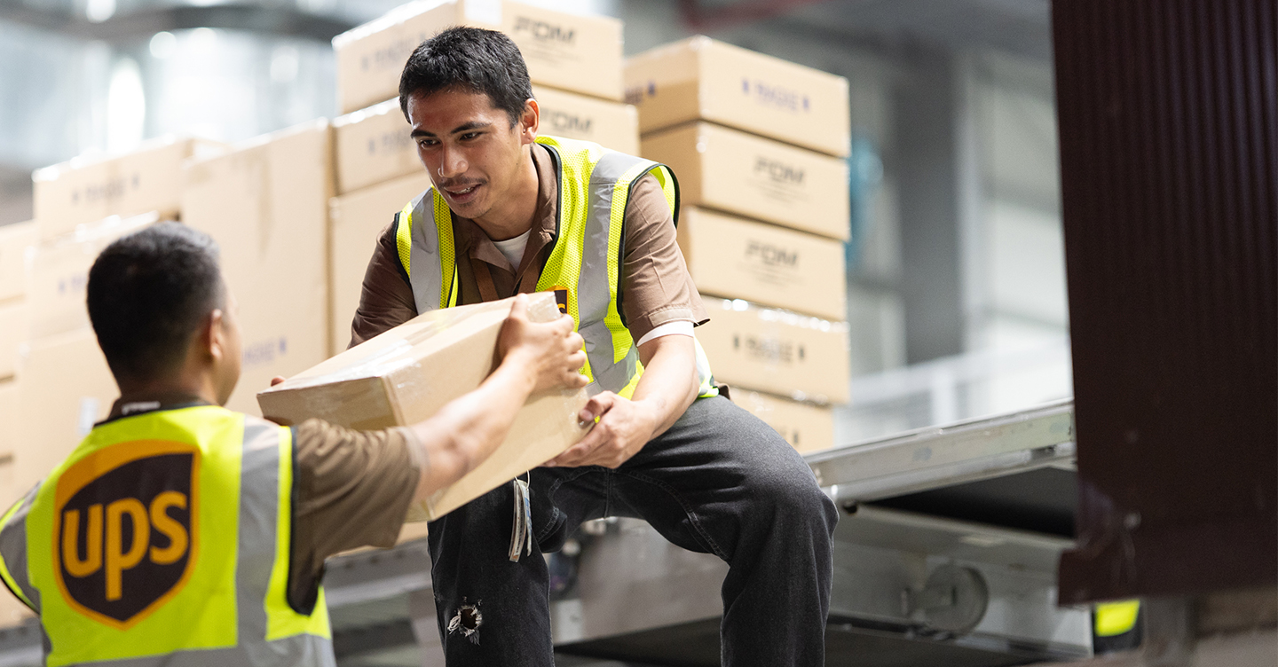 UPS workers loading cardboard boxes in warehouse