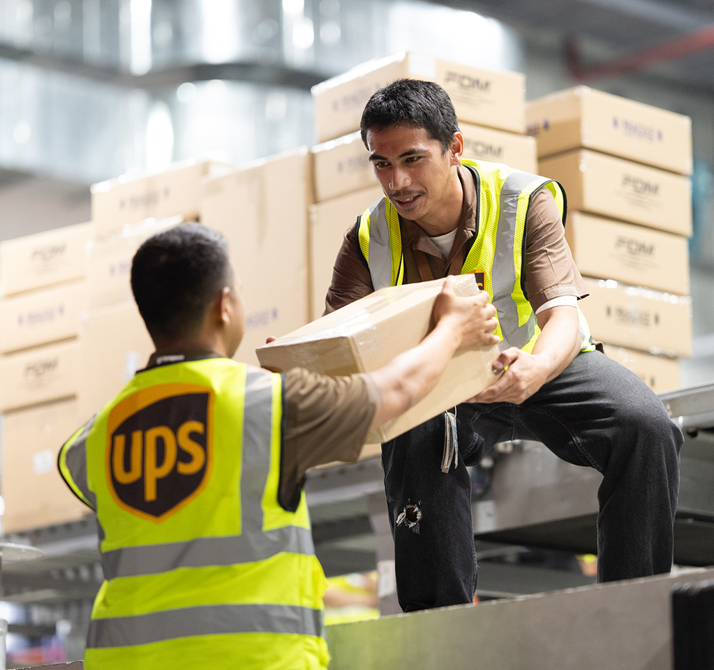 Warehouse workers handling parcel on conveyor