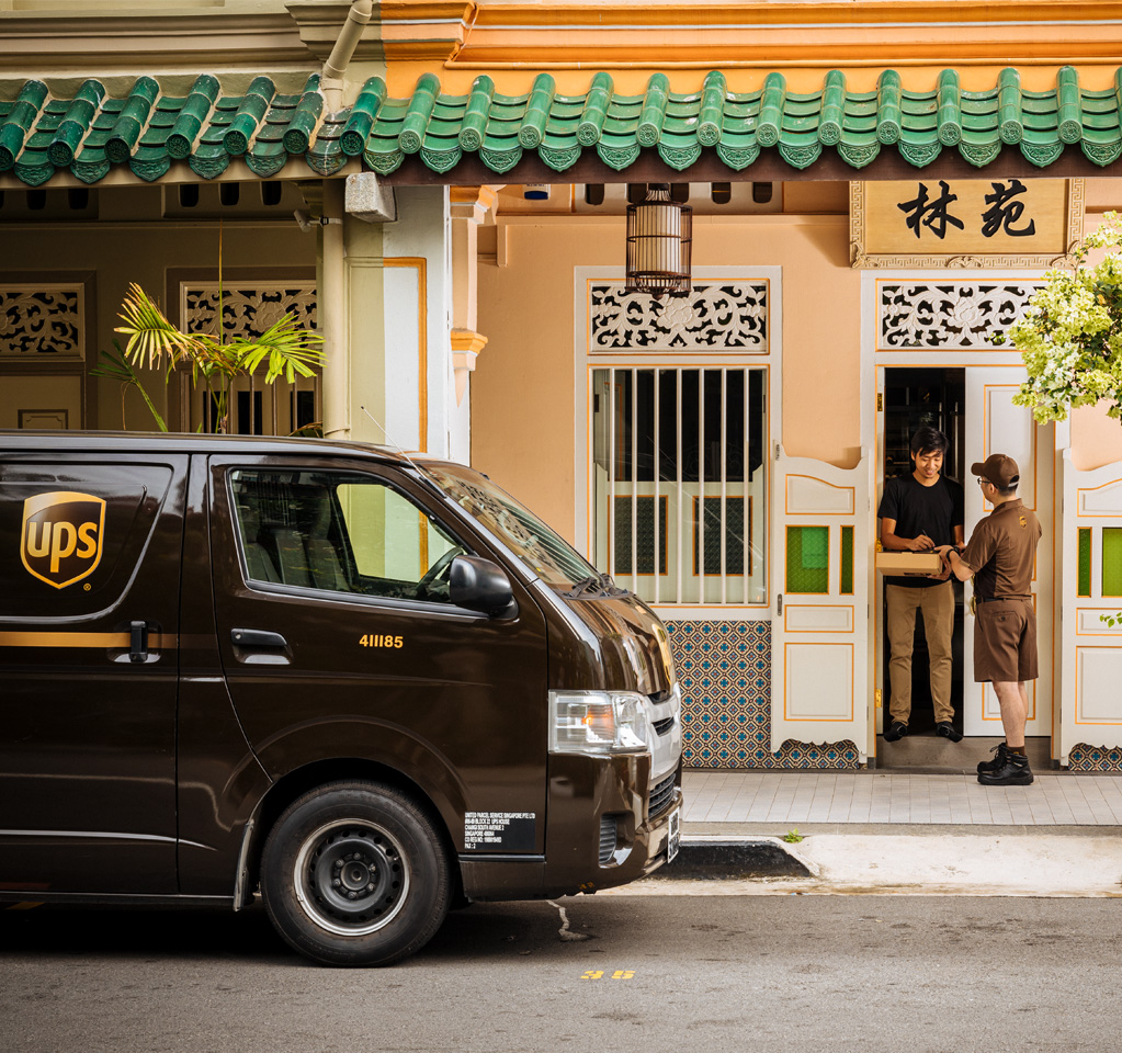 Courier delivers package to traditional shophouse doorway