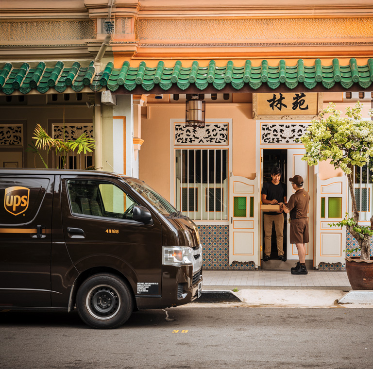 Courier delivers package to traditional shophouse doorway