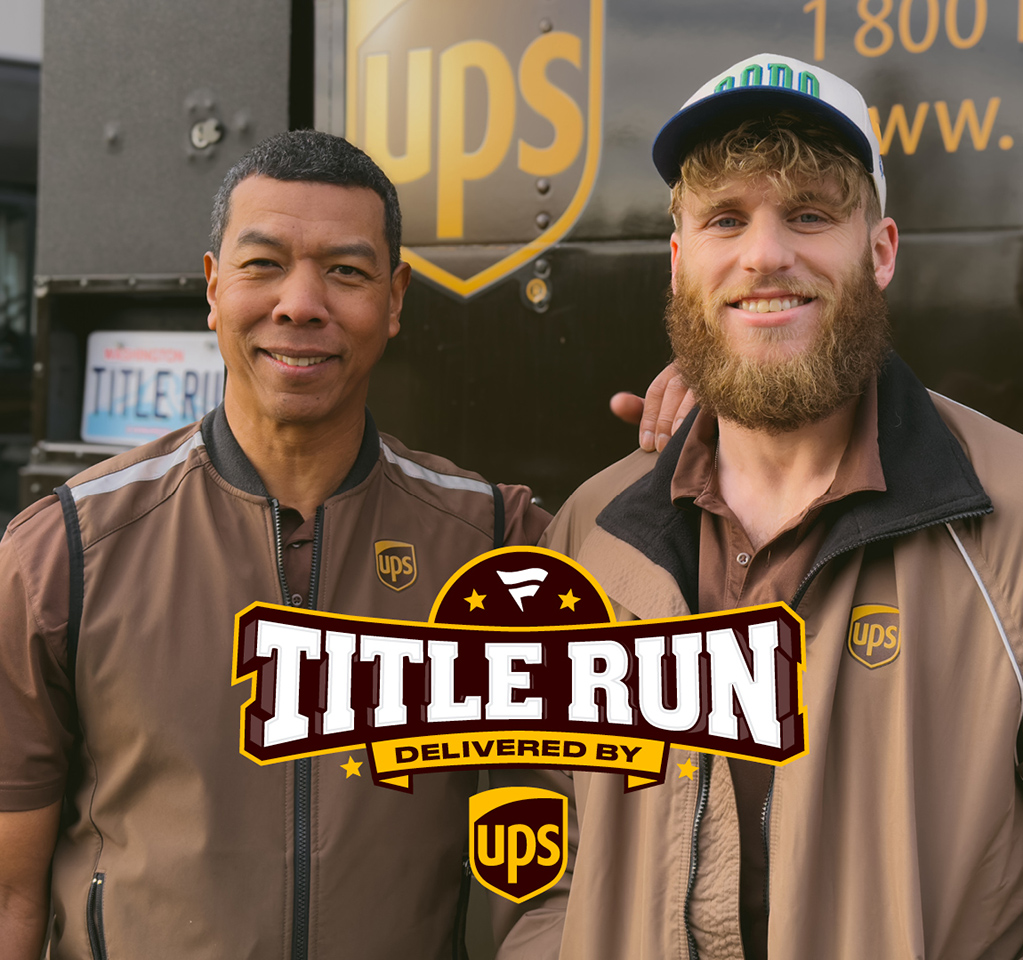 UPS driver and NFL player smiling at back of UPS vehicle