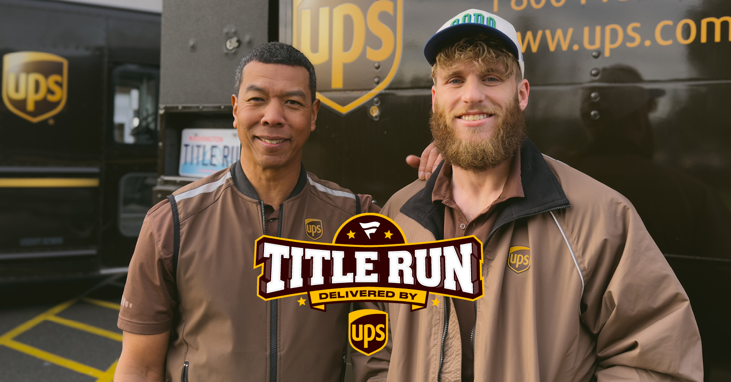UPS driver and NFL player smiling at back of UPS vehicle