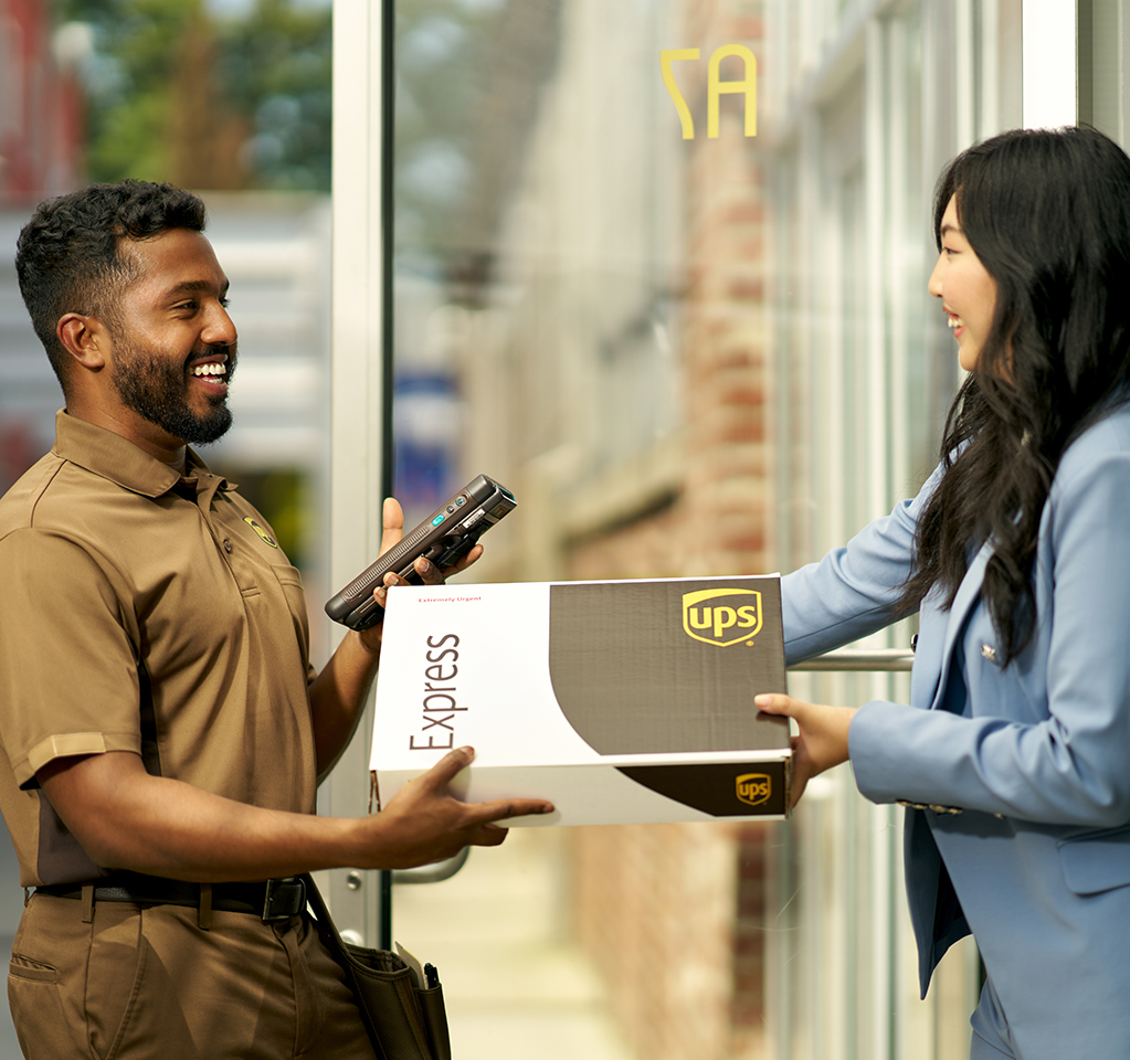 A UPS driver handing a UPS Express box to a small business customer.