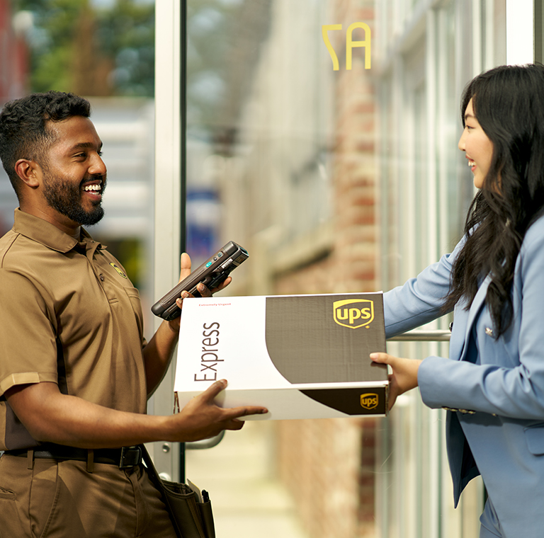 A UPS driver handing a UPS Express box to a small business customer.