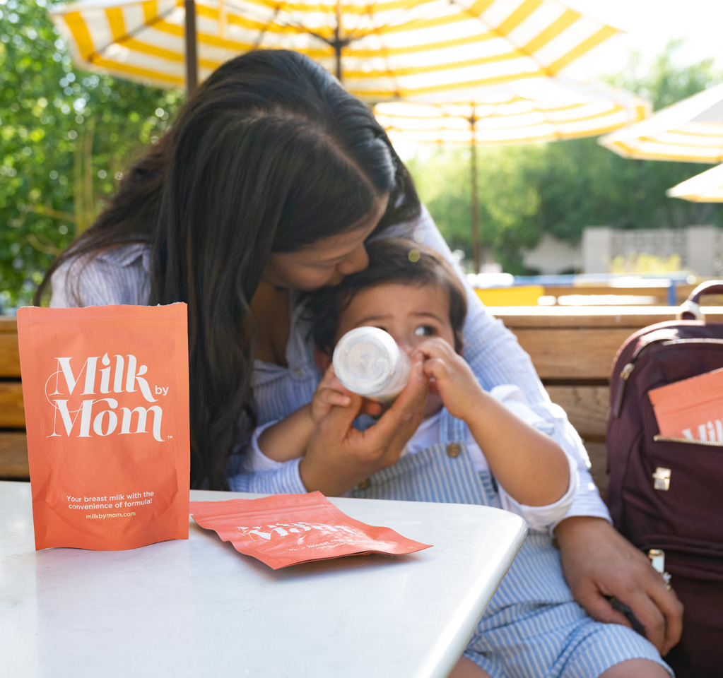 Mãe amamentando o bebê com a bolsa Milk by Mom