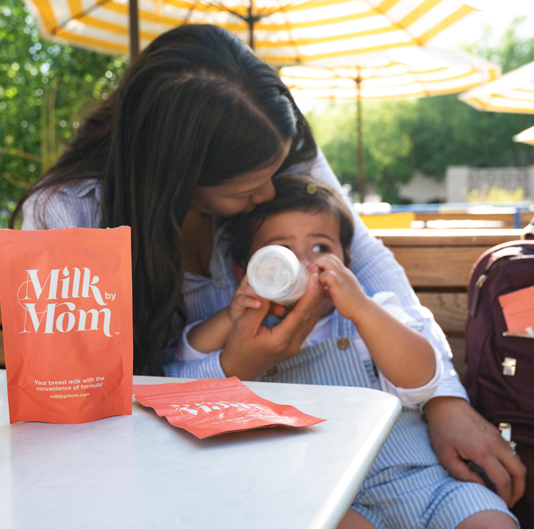 Mãe amamentando o bebê com a bolsa Milk by Mom