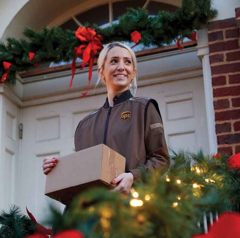 Personne chargée de la livraison tenant le colis pendant les fêtes